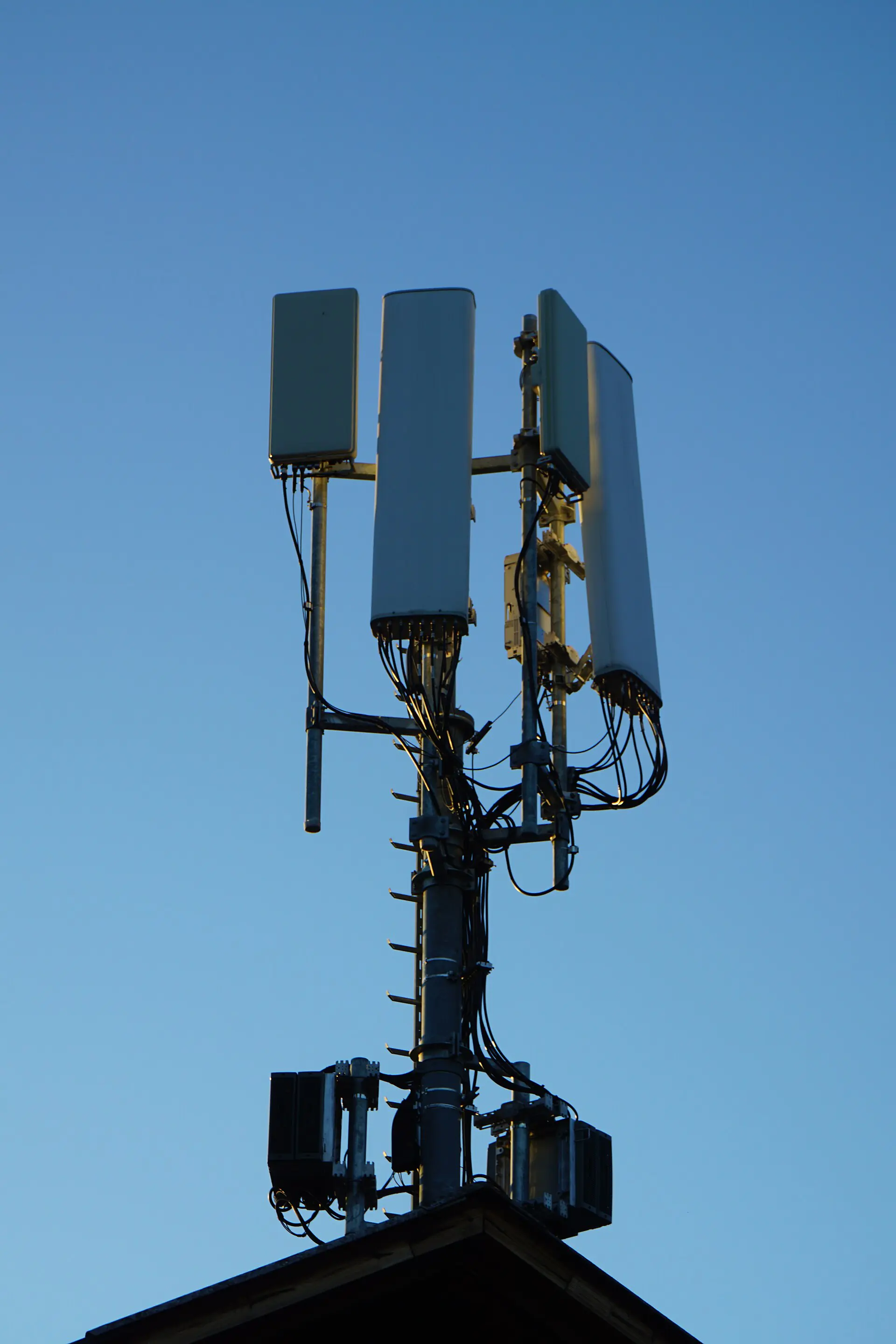 Mobilfunk-Basisstation mit mehreren Antennen vor blauem Himmel