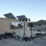 Kleine Freiluftbühne mit Scheinwerfern an einer Traverse, Lautsprechern auf Stativen und Technikpult